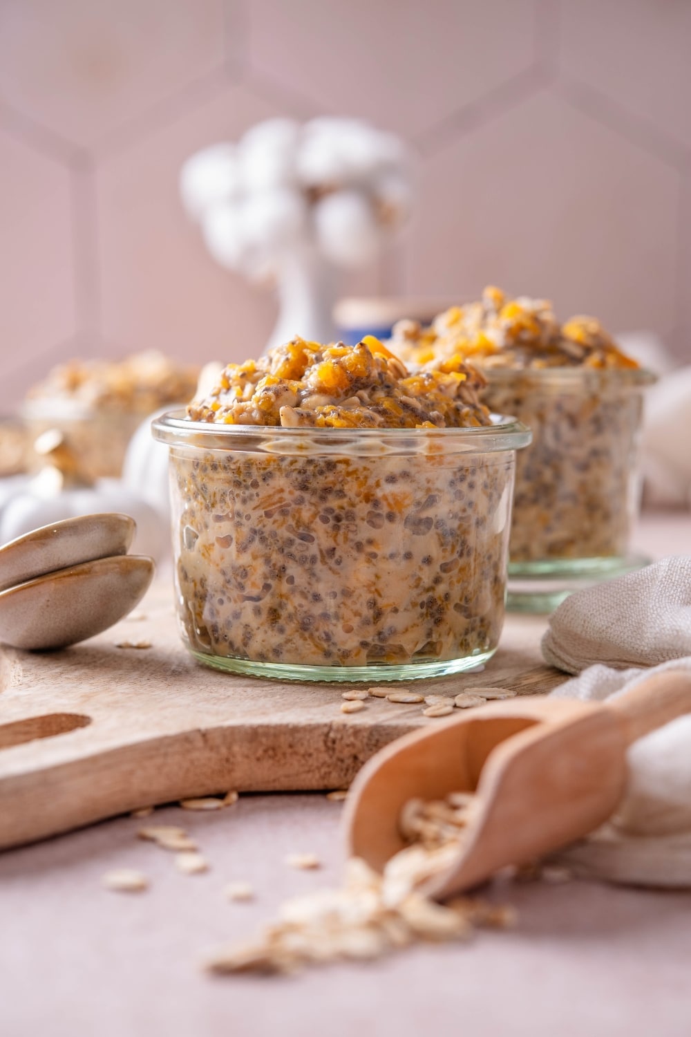 A glass jar filled with pumpkin overnight oats on top of a wooden serving board.