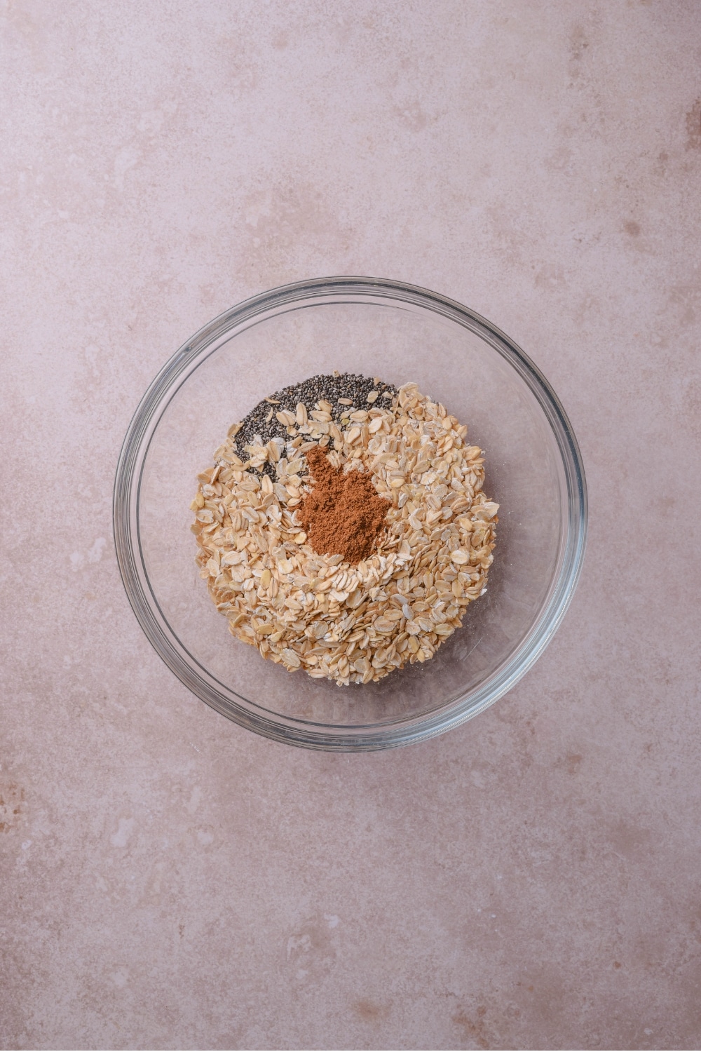 A glass bowl filled with oats, chia seeds, and pumpkin pie spice on top.