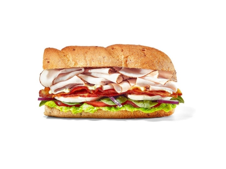 A sub with turkey, bacon, lettuce, tomato, and spinach.