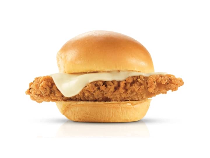 A bun with cheese and a chicken finger between it.