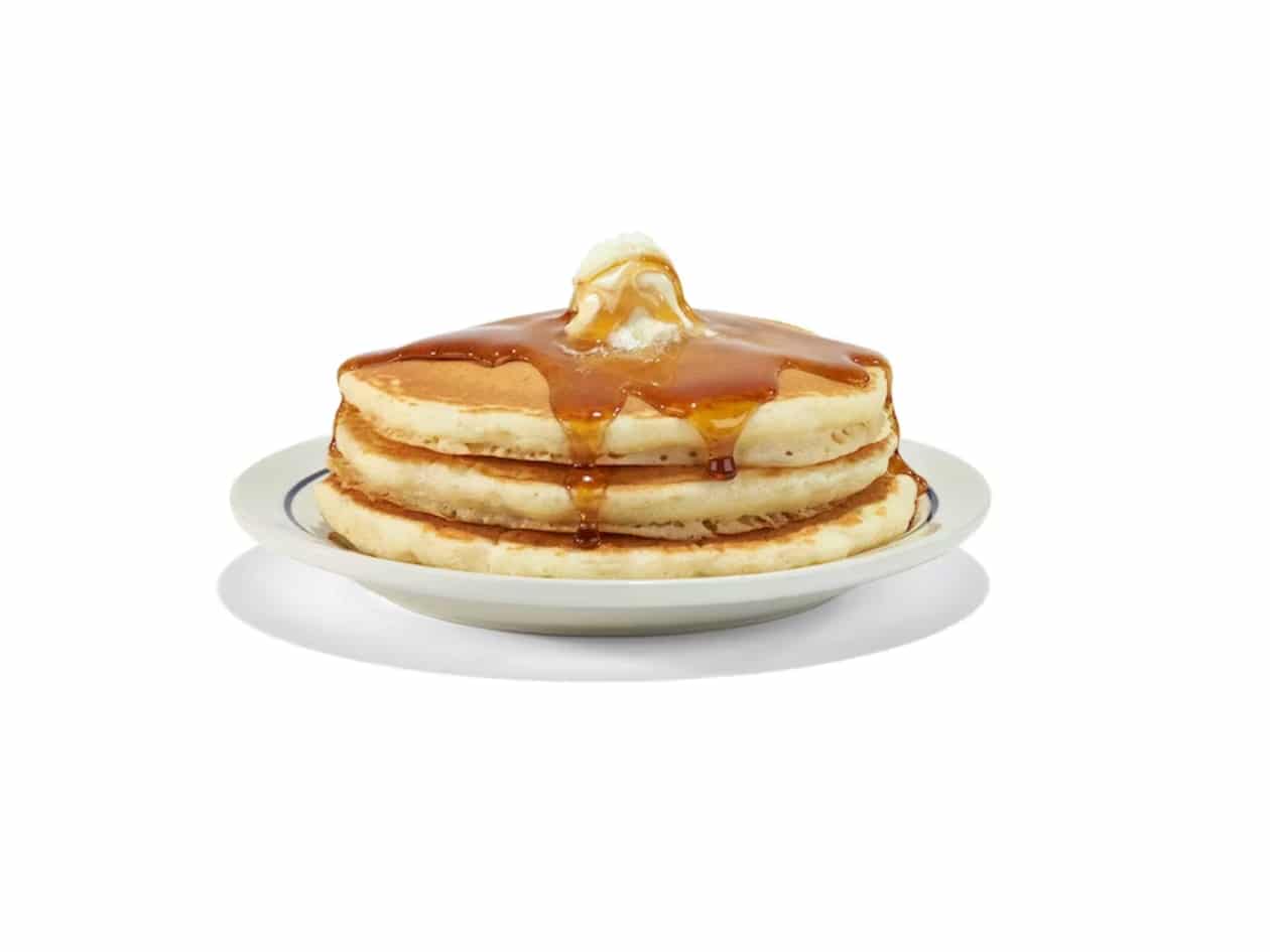 A stack of three buttermilk pancakes with butter and syrup on top.