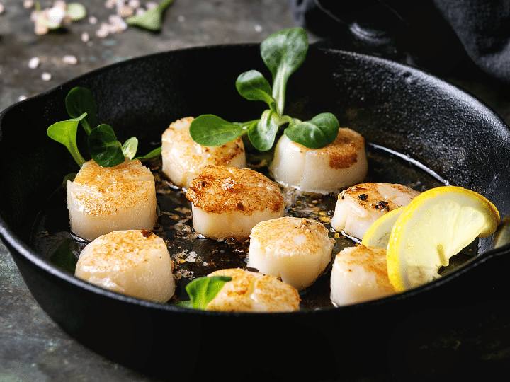 A bunch of scallops in a skillet.