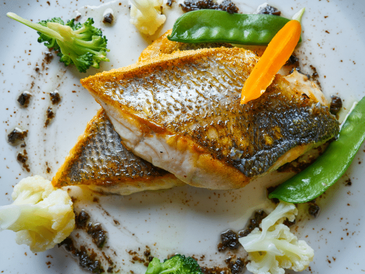 A piece of cooked sea bass on top of another piece of sea bass.