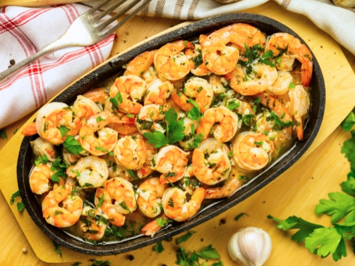 A bunch of cooked shrimp stacked over one another in an oval plate.