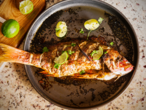 A whole cooked snapper in a skillet.