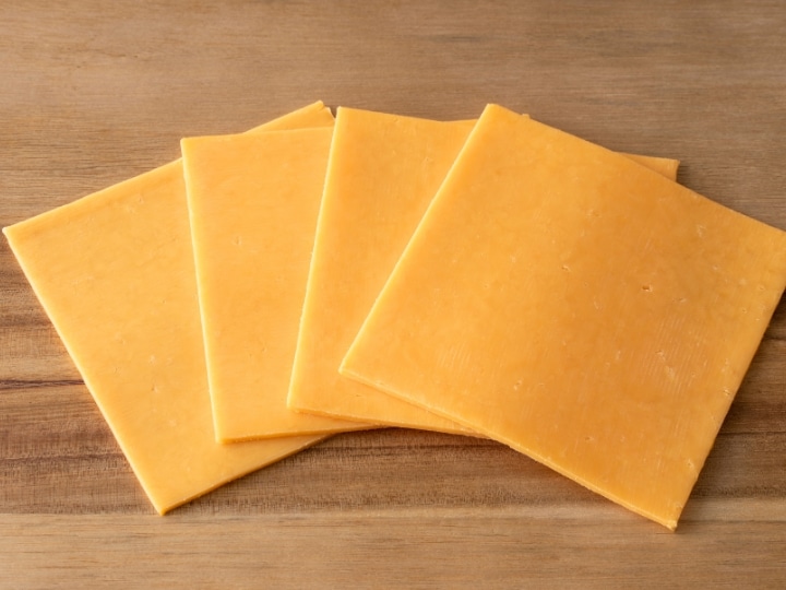 Four slices of cheddar cheese overlapping one another.