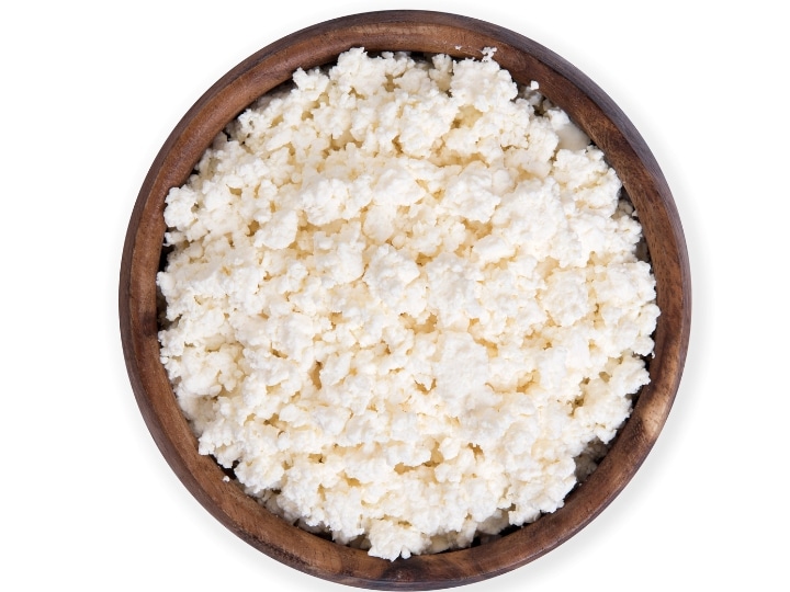 A bunch of cottage cheese crumbles in a wooden bowl.