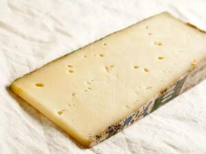 A block of fontina cheese on a white counter.