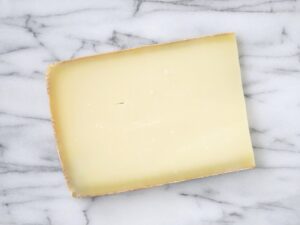 A slice of gruyere cheese on a grey counter.