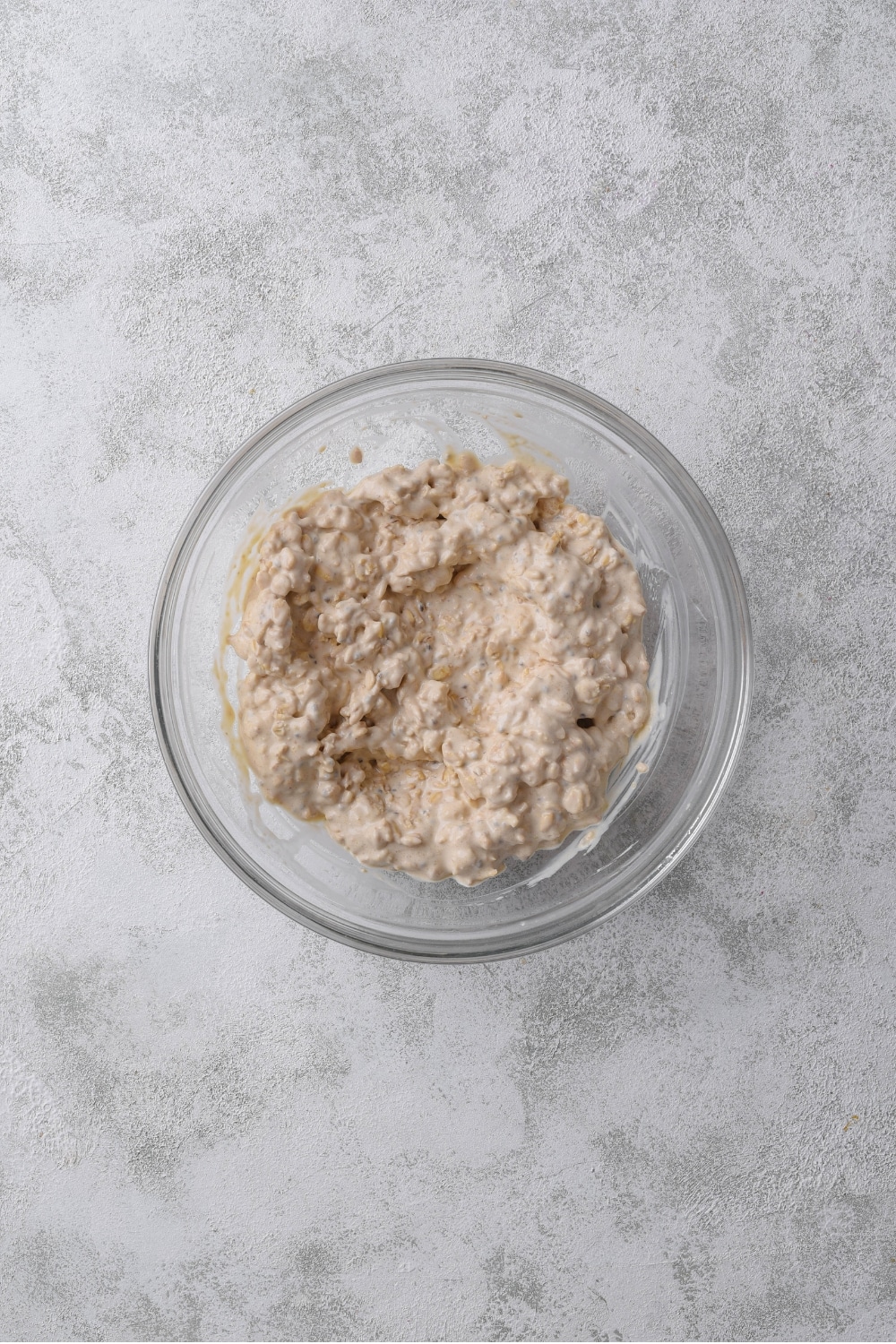 An overhead shot of a glass bowl filled with soaked peanut butter overnight oats.
