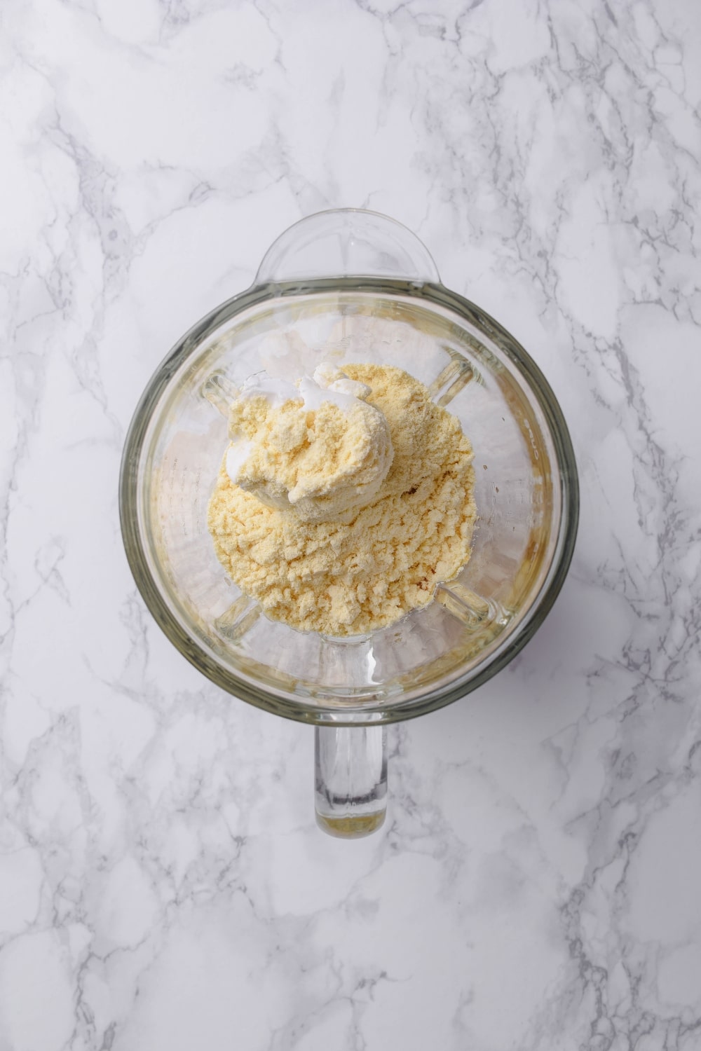 A glass blender with vanilla protein powder, coconut milk, sugar, and vanilla.