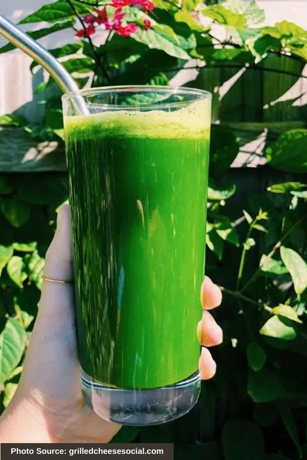 A hand holding a glass of Kale Juice.