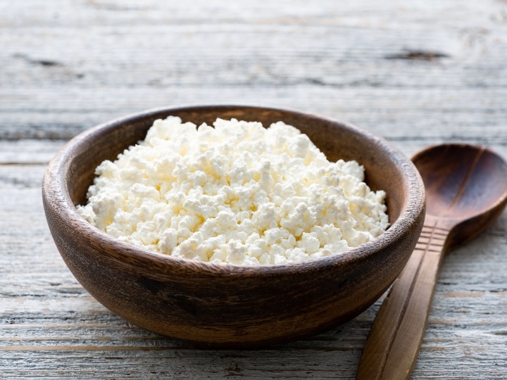 A wood bowl of ricotta cheese on a grey counter.