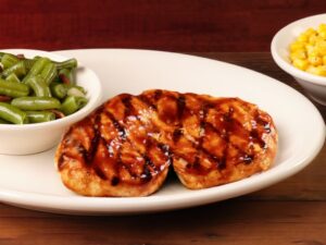 A piece of barbecue chicken on a white plate.