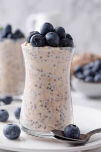 Blueberries on top of overnight oats in a glass jar.