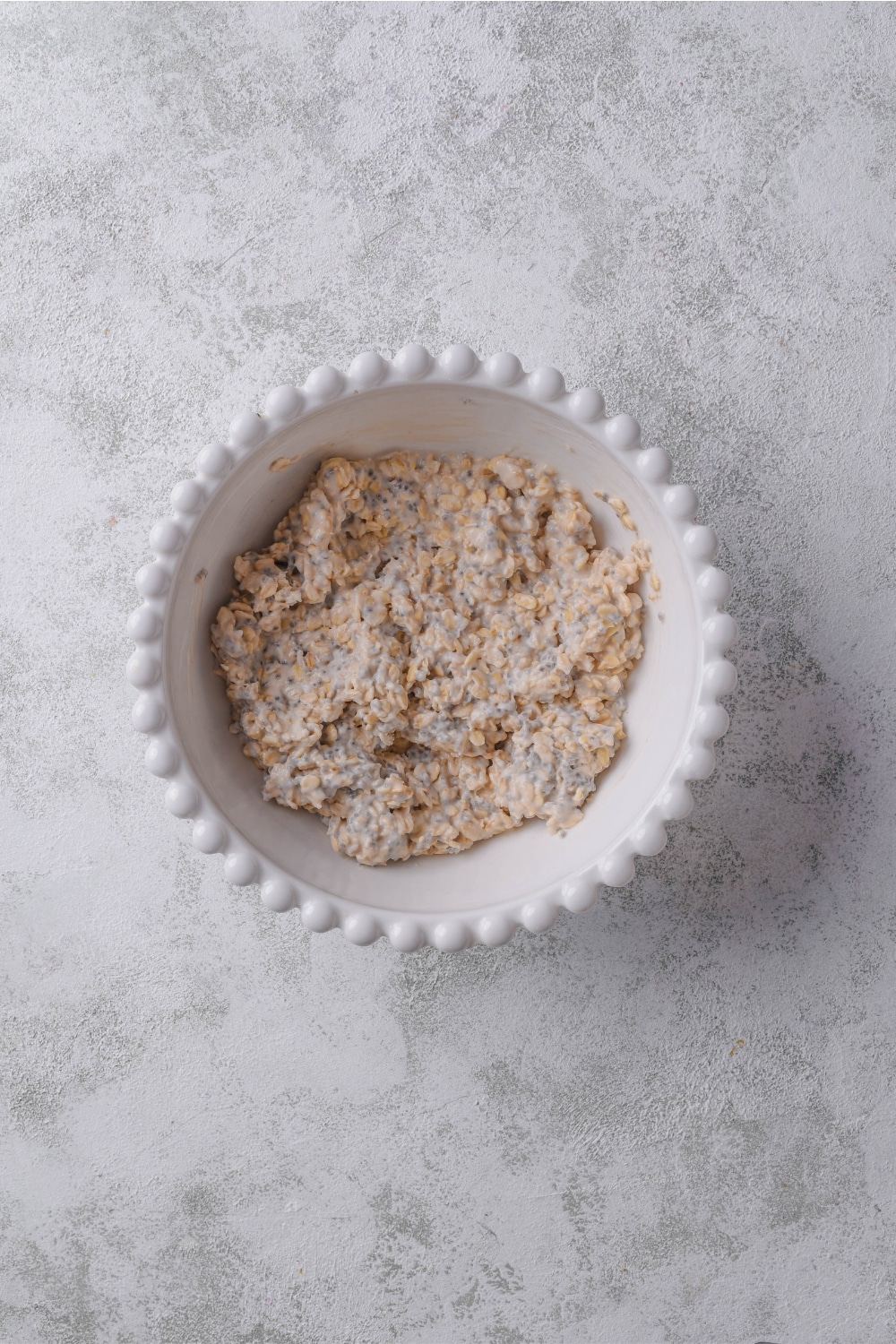 A ceramic bowl filled with an overnight oats mixture with oats, milk, and chia seeds.