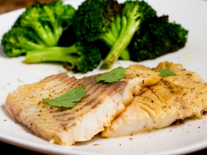 Two pieces of cooked tilapia on a plate.