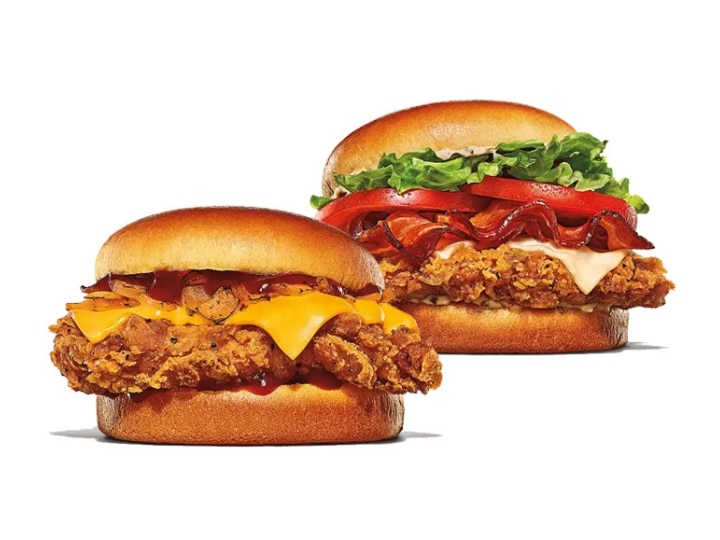 Two crispy chicken sandwiches, one with bacon, tomato, and lettuce, and one with cheese.