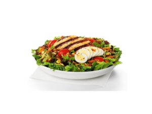 Chopped egg and a grilled chicken breast on top of lettuce.