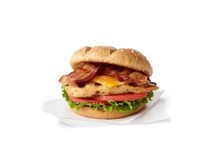 A grilled chicken, bacon, and cheese sandwich with tomato and lettuce.