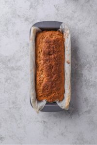 An overhead shot of low calorie banana bread baked in a loaf pan lined with parchment paper
