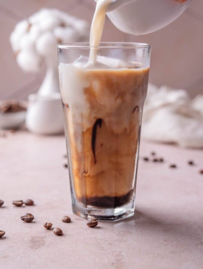 A tall glass of low calorie iced coffee with milk being poured into the glass.
