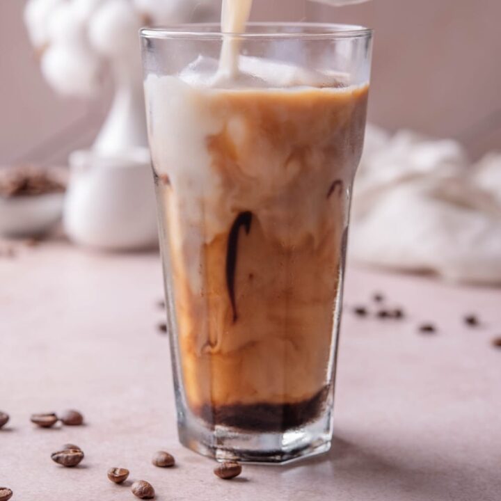 A tall glass of low calorie iced coffee with milk being poured into the glass.