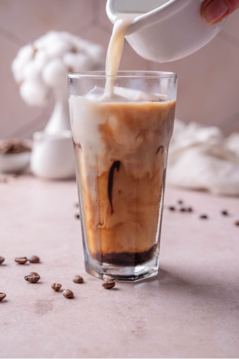 A tall glass of low calorie iced coffee with milk being poured into the glass.