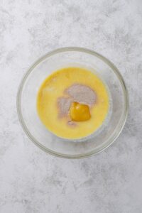An overhead shot of a glass bowl with an oat, egg, and yeast mixture.