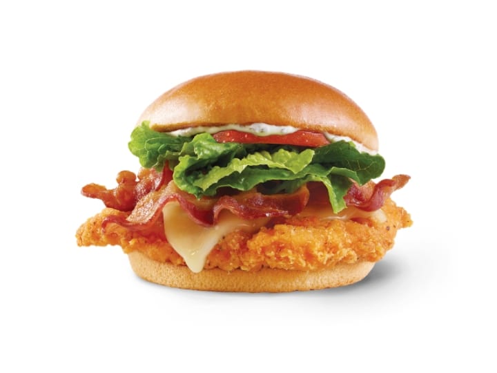 A crispy chicken sandwich with lettuce, tomato, spicy sauce, bacon and cheese.