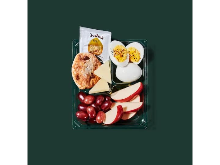 A box with grapes, apples, hard boiled eggs, and pita.