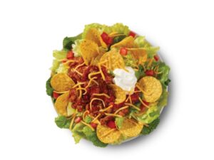 Tortilla chips and bacon with cheese and sour cream on top of lettuce.