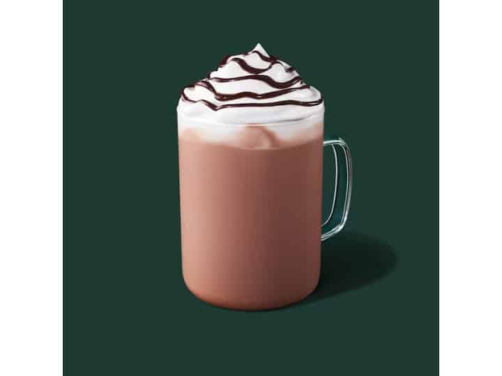 A clear cup of starbucks hot chocolate with whipped cream on top.