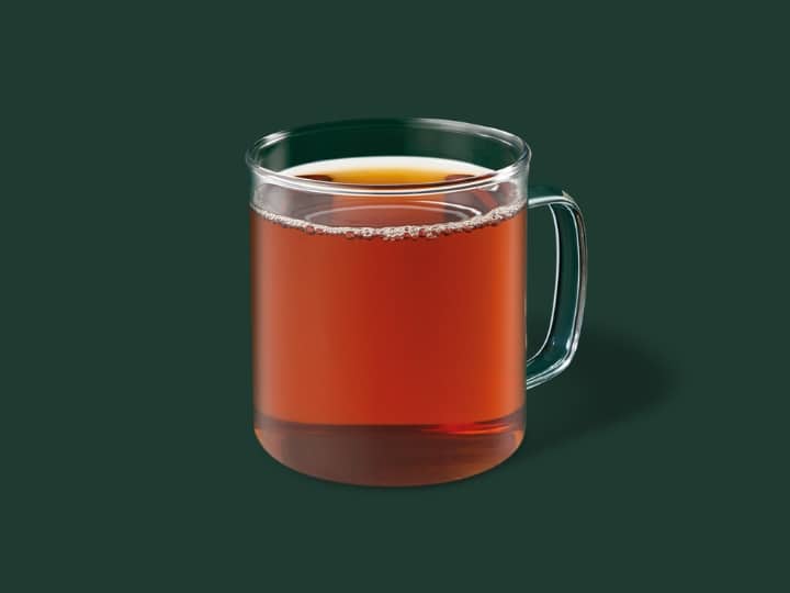 A glass cup of starbucks hot tea.