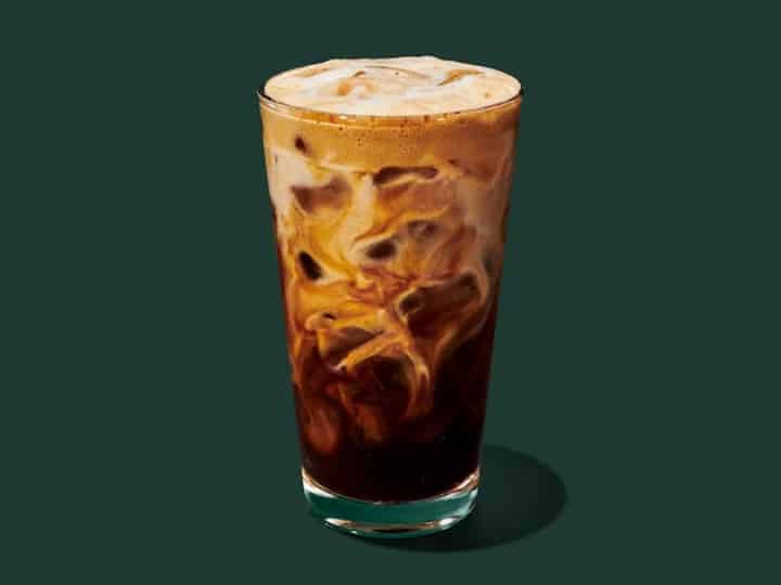A cup of starbucks Iced Hazelnut Oat Milk Shaken Espresso.