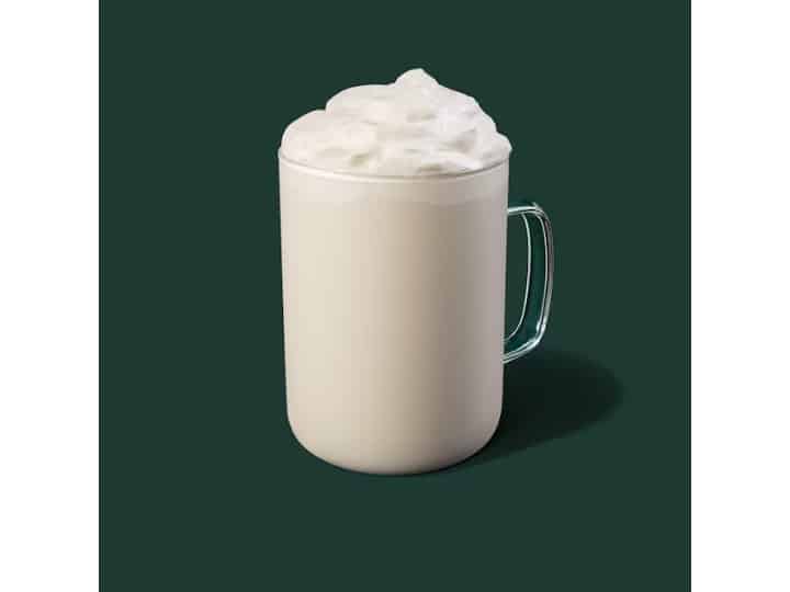 A clear cup of starbucks white hot chocolate with whipped cream.