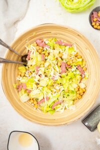 An overhead shot of a large salad bowl filled with the la scala chopped salad. The salad includes chopped lettuce, chick peas, salami, and shredded mozzarella.
