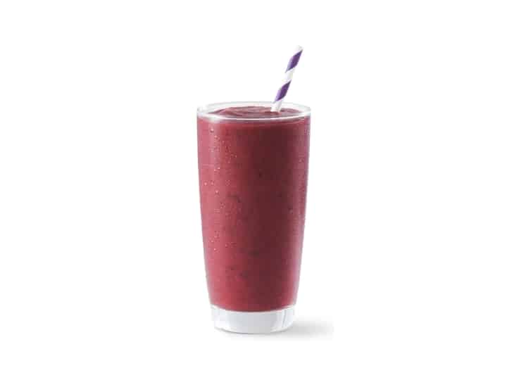 A glass cup filled with a blueberry smoothie.