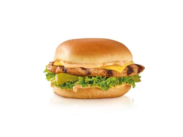 A grilled chicken sandwich with lettuce, sauce and cheese.