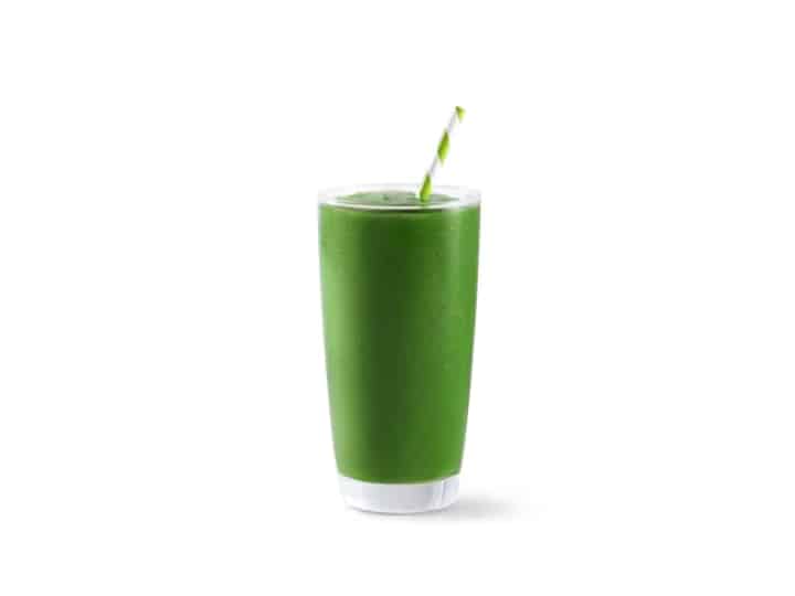 A glass cup filled with a green smoothie.