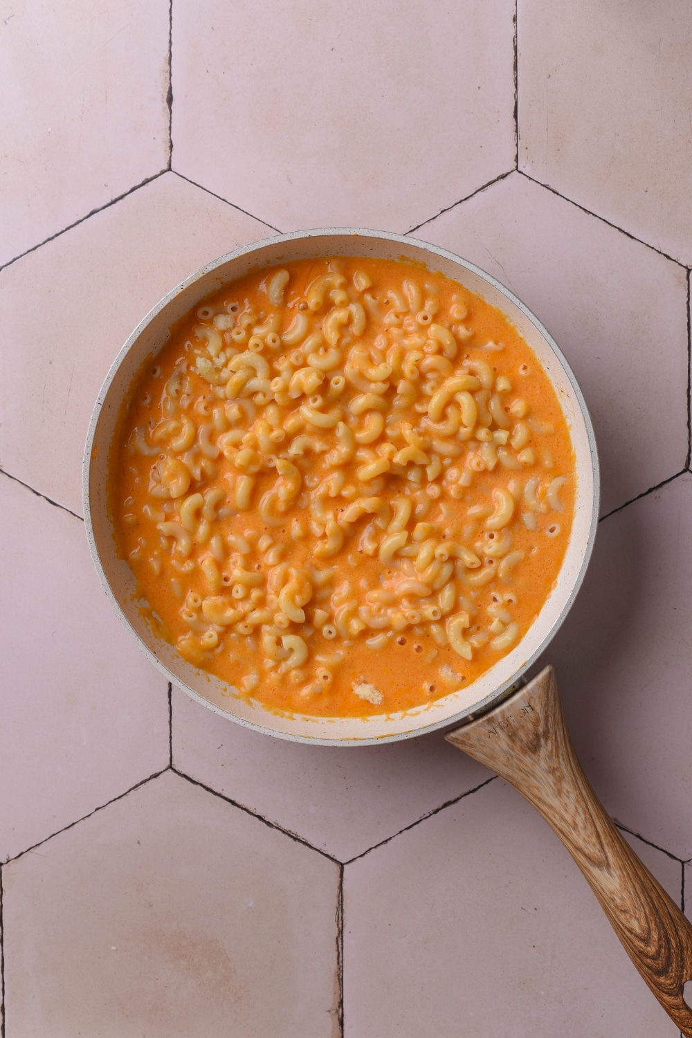 An overhead shot of a ceramic pan filled with macaroni cooking in a cheese sauce.