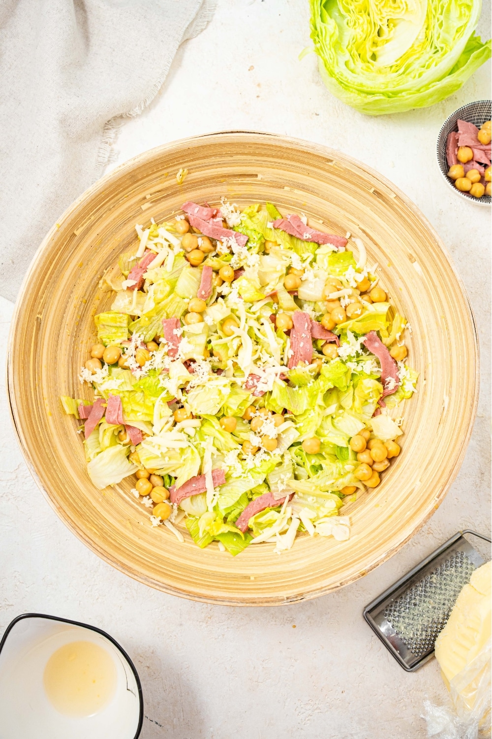 An overhead shot of a large salad bowl filled with the la scala chopped salad. The salad includes chopped lettuce, chick peas, salami, and shredded mozzarella.