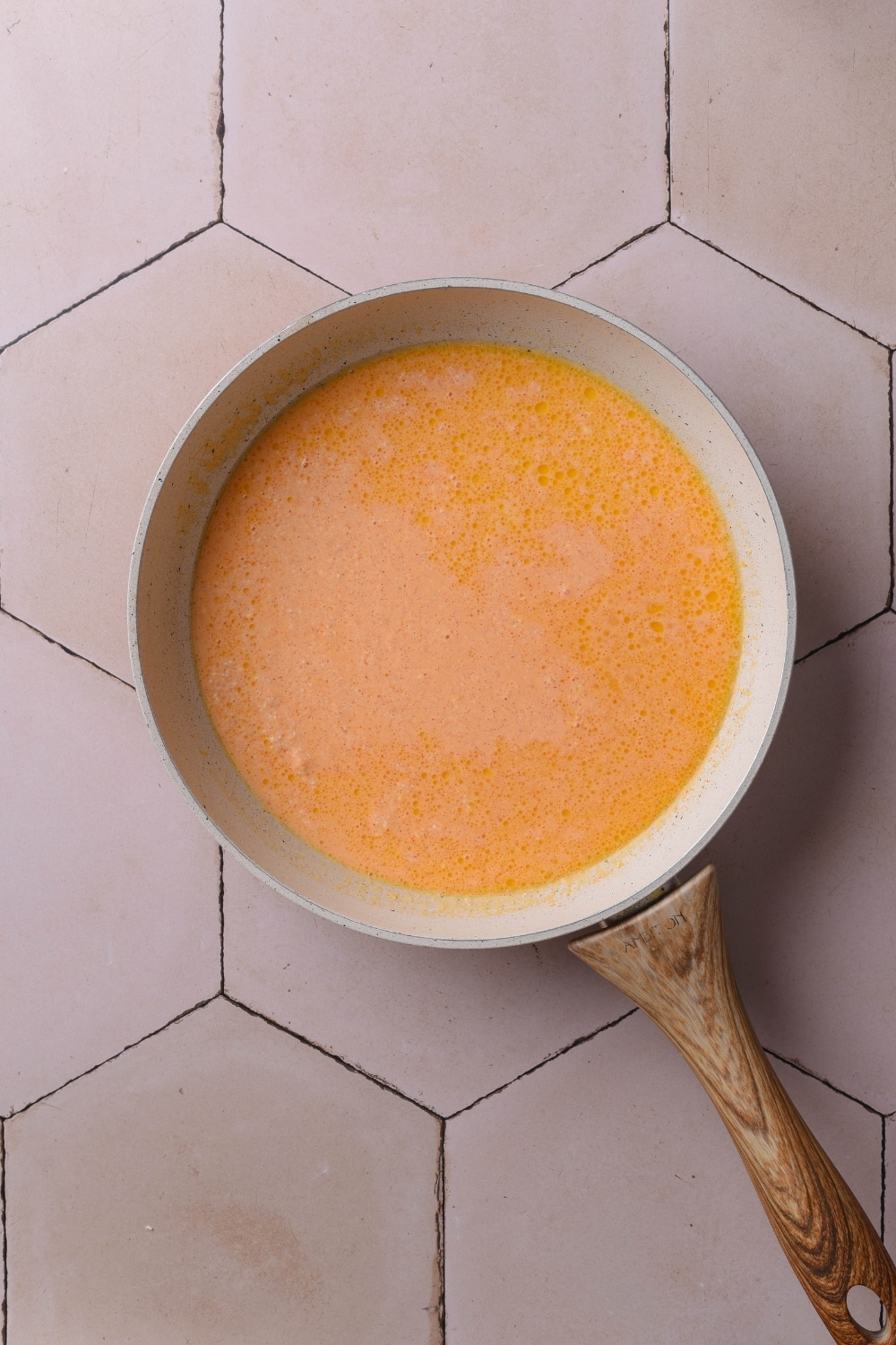 An overhead shot of a ceramic pan filled with cheese sauce.