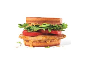 A sourdough bun with lettuce, tomato, and grilled chicken between it.
