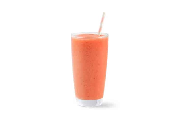 A glass cup filled with a pink smoothie.