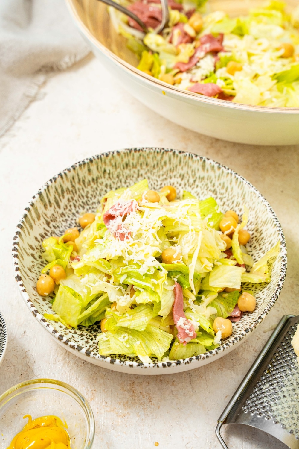 A salad bowl filled with the la scala chopped salad. The salad consists of chopped lettuce with chick peas, salami, and topped with shredded mozzarella.