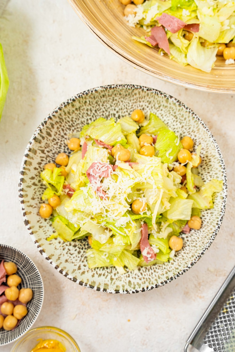 An overhead shot of a salad bowl filled with the la scala chopped salad. The salad includes chopped lettuce, chick peas, salami, and shredded mozzarella.