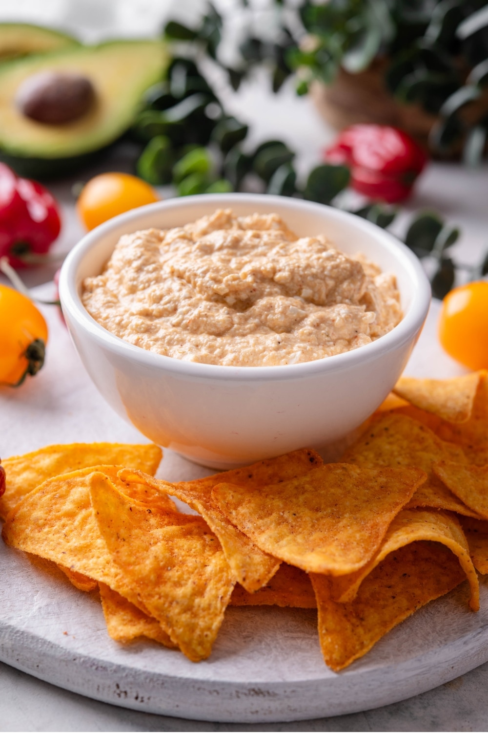 A bowl of low calorie queso dip on a wooden serving board with tortilla chips.