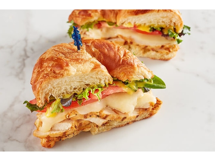 A croissant with lettuce, tomato, and grilled chicken.