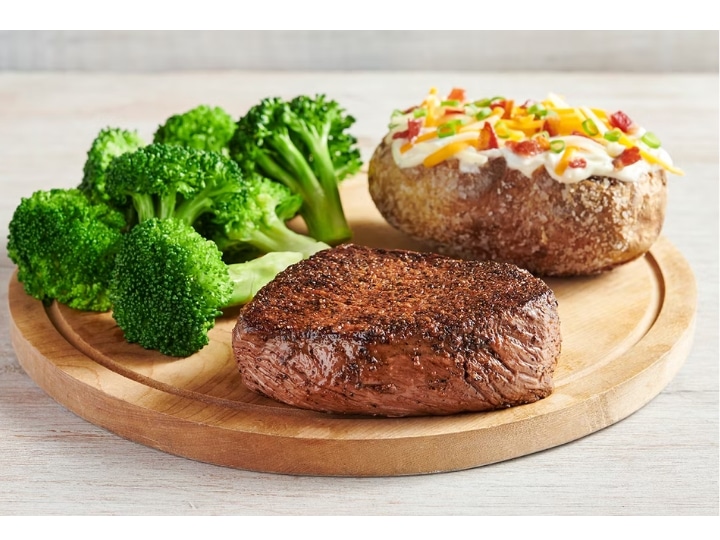 A piece of sirloin steak with broccoli and a baked potato.